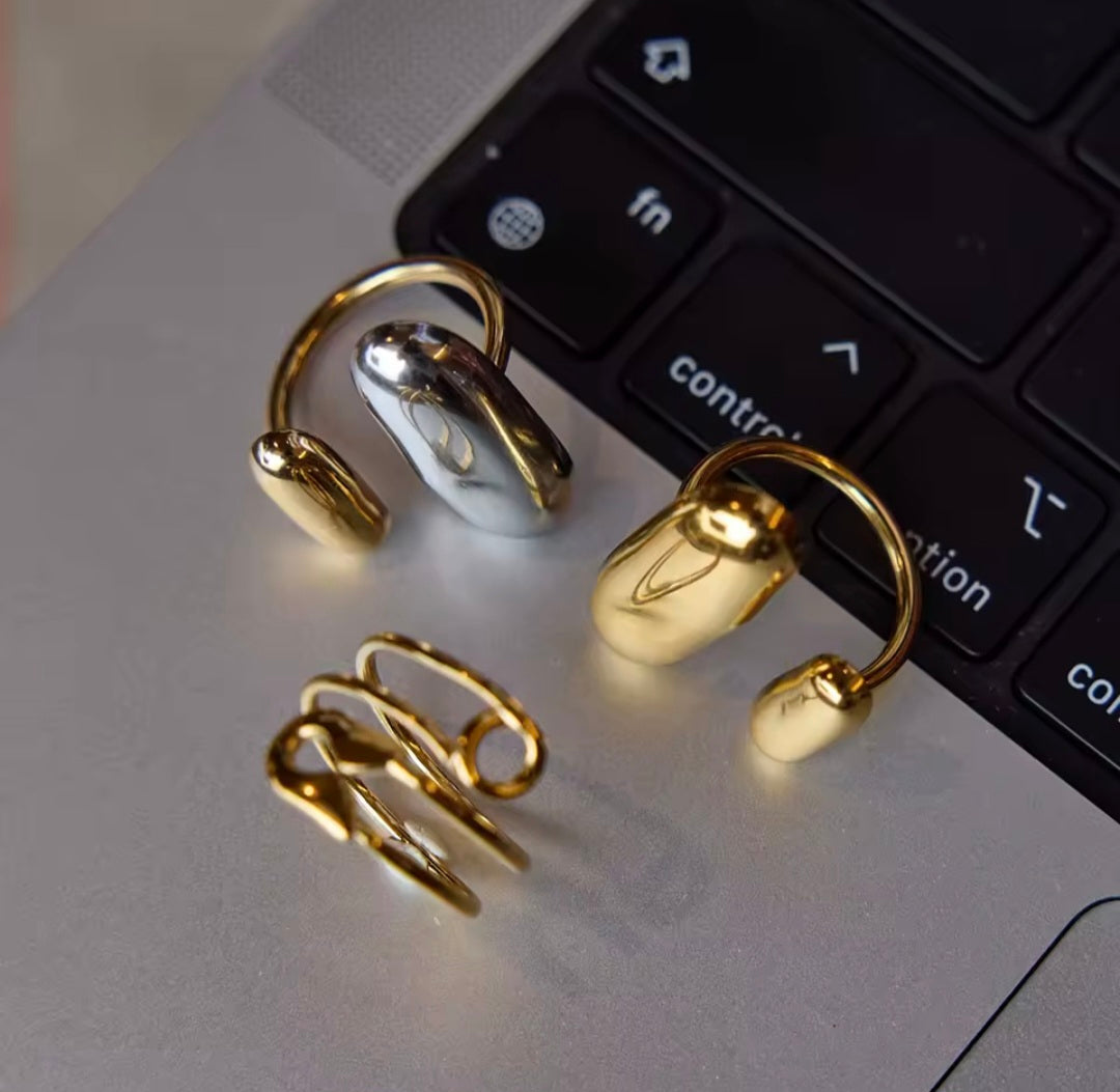 Conjunto de anéis em aço inoxidável estilo tendência mix nas cores dourado e prateado sobre teclado preto.
